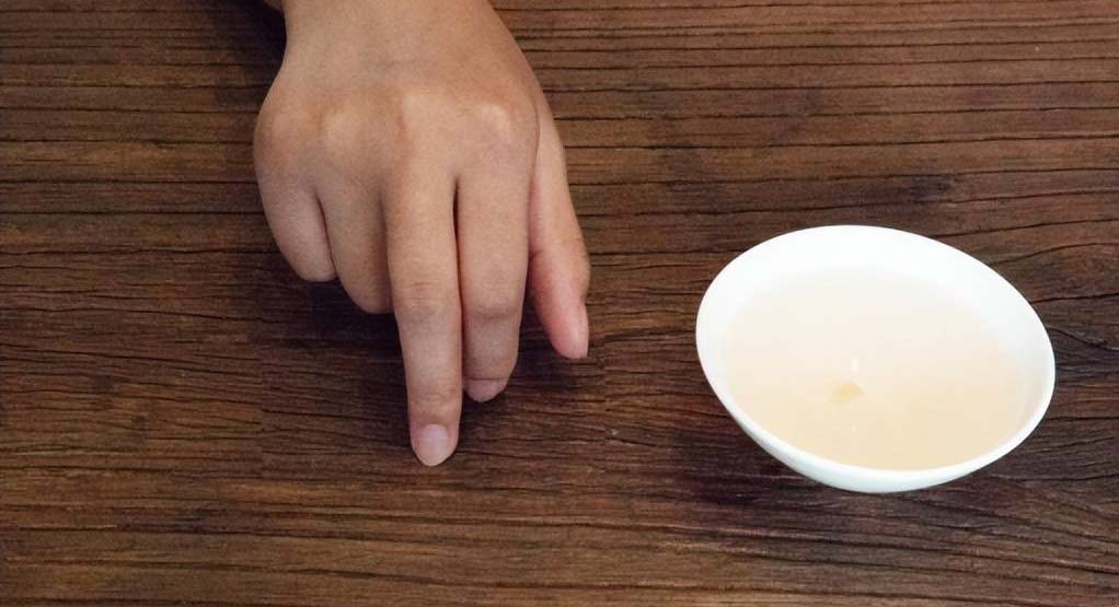 Chinese tea pouring etiquette showing finger tap thank you gesture
